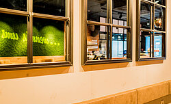 Markenbotschaft in apfelgrün integriert in Mooswand moosgrün, Evergreen Moos Premium, Freund, Café in Wien